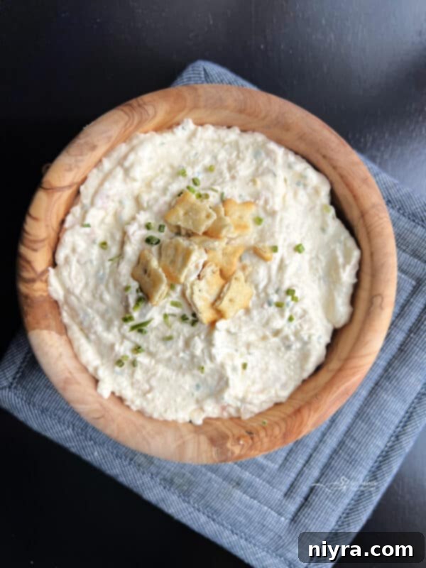Savory Chicken Cracker Dip 9 A side view of the creamy Chicken in a Biskit Dip in a white bowl, with crackers in the background.