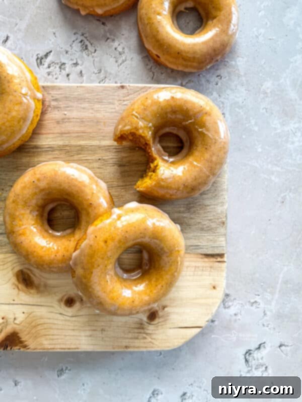 Glazed Baked Pumpkin Donut with a bite taken out, on a white plate.