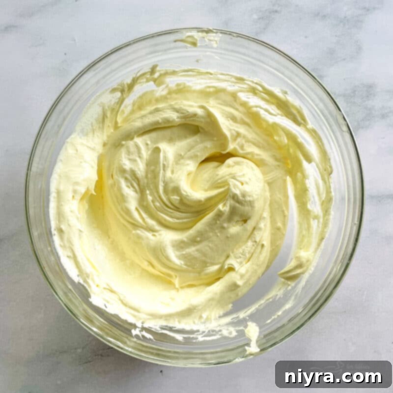 Heavy whipping cream being beaten to stiff peaks in a mixing bowl.