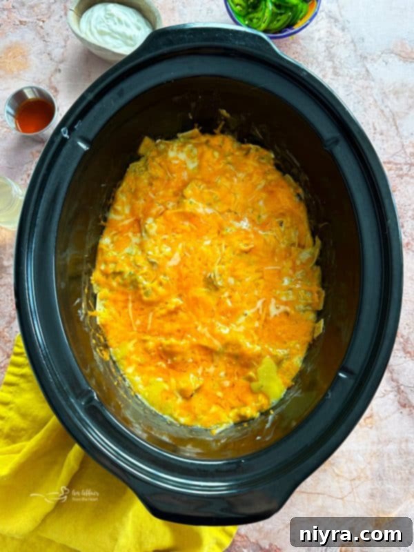 Close-up of Slow Cooker Green Chile Chicken Enchilada Casserole with melted cheese and green onions