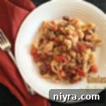 Overhead of Goulash on a white plate with a fork and a red napkin on a dark surface. Text "Goulash"