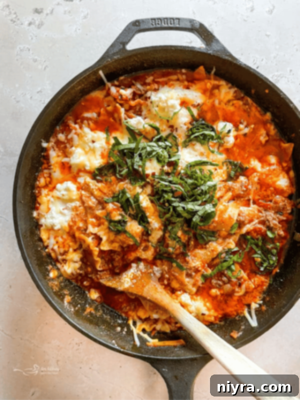 Overhead of skillet lasagna with a serving spoon in it.