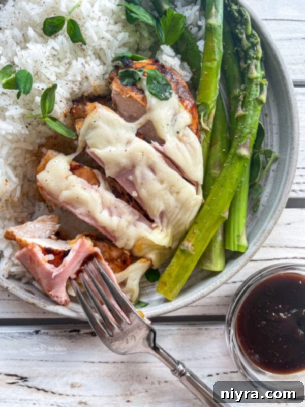 Grilled chicken topped with melted provolone cheese and ham, served with asparagus spears.