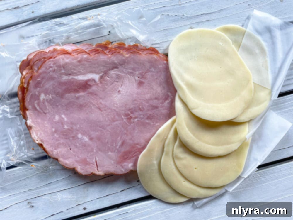Slices of ham and provolone cheese, ready to be layered onto the grilled chicken.