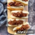 Hot dogs with chili on them on a wood board