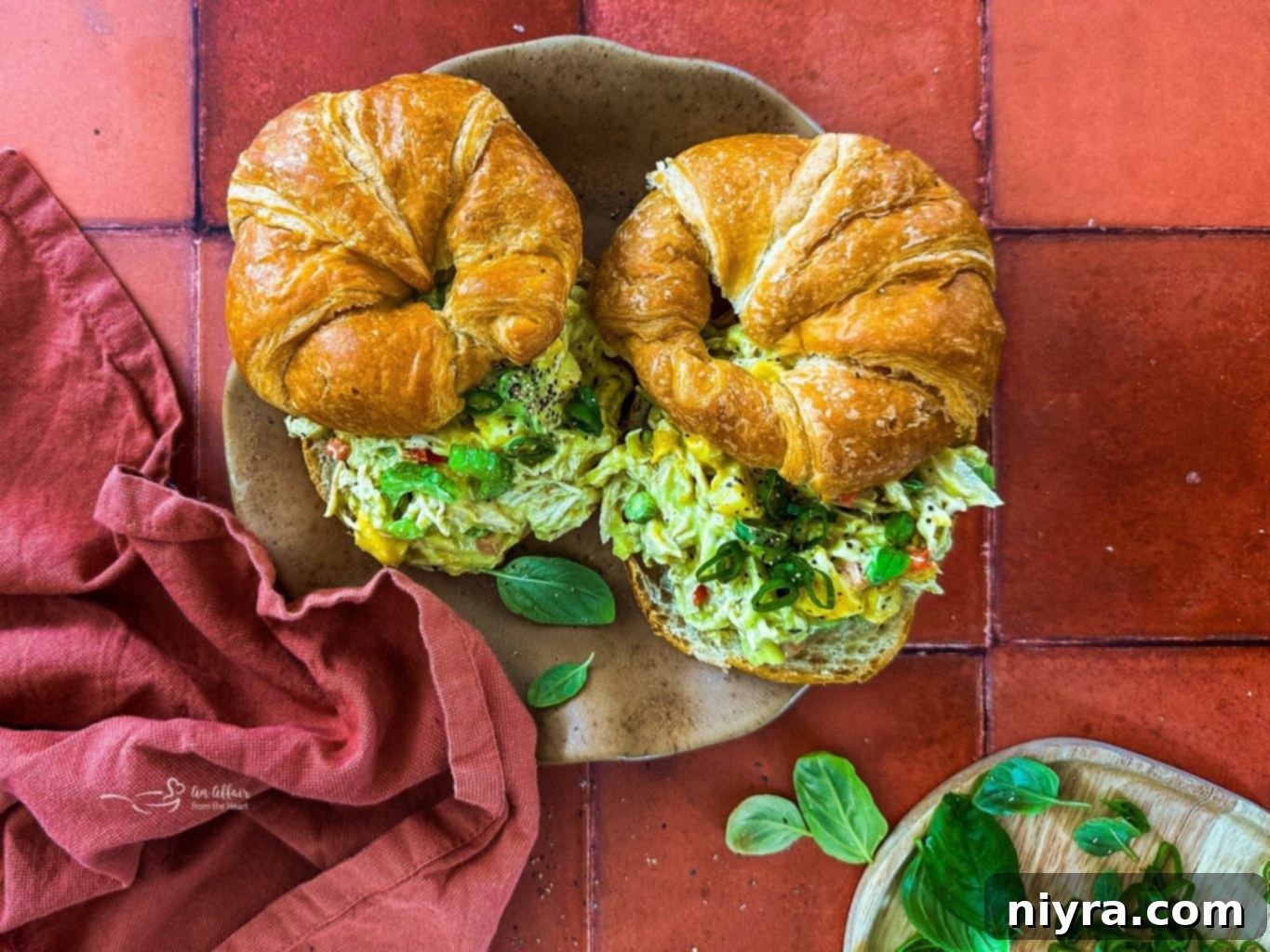 Two Croissants stuffed with Peach Basil Chicken Salad, served on a white plate, indicating other delicious salad recipes.