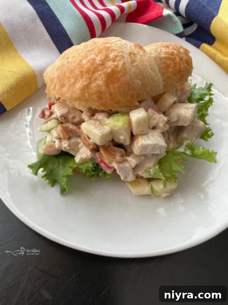 A delicious Apple Chicken Salad sandwich on a white plate, served with fresh greens, highlighting a perfect meal idea.