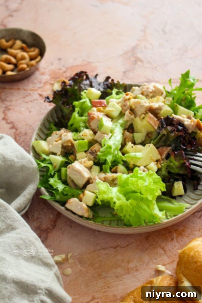 Close-up of a serving of Apple Chicken Salad, showing the rich texture of shredded chicken, bright apple pieces, and visible nuts, tossed in a creamy dressing.