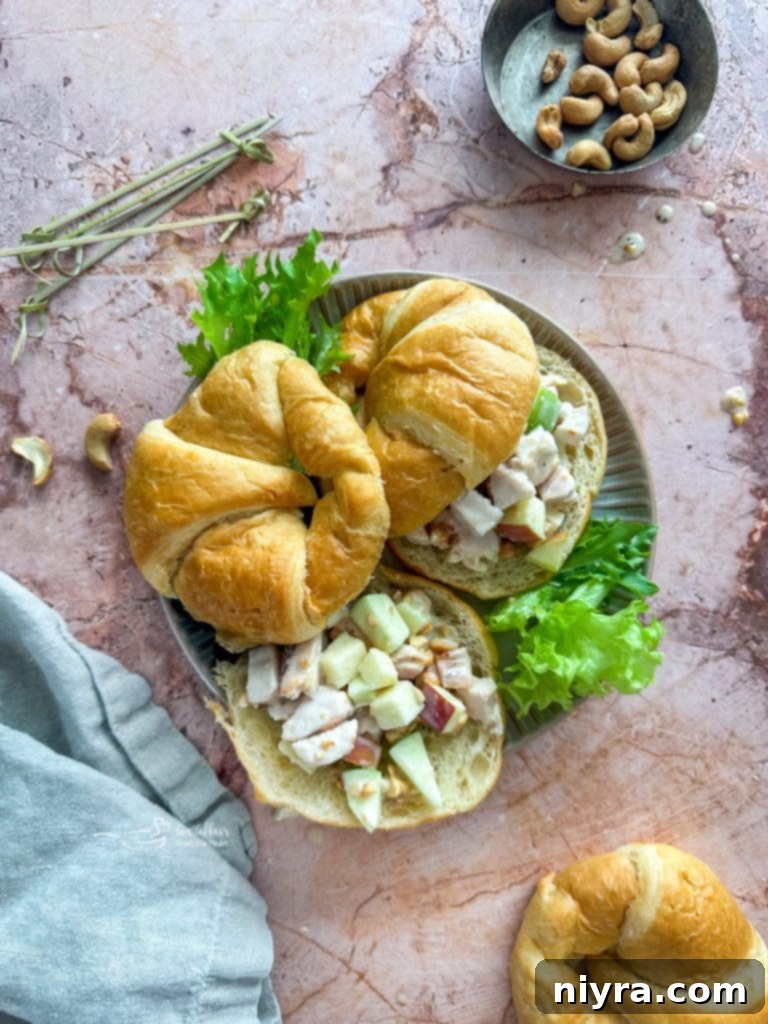 A bowl of Apple Chicken Salad with a spoon, ready to be served, emphasizing its fresh appearance and vibrant ingredients.