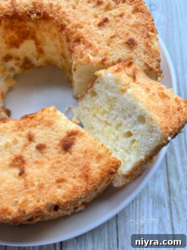 Slice of Pineapple Angel Food Cake on a white plate with a fork