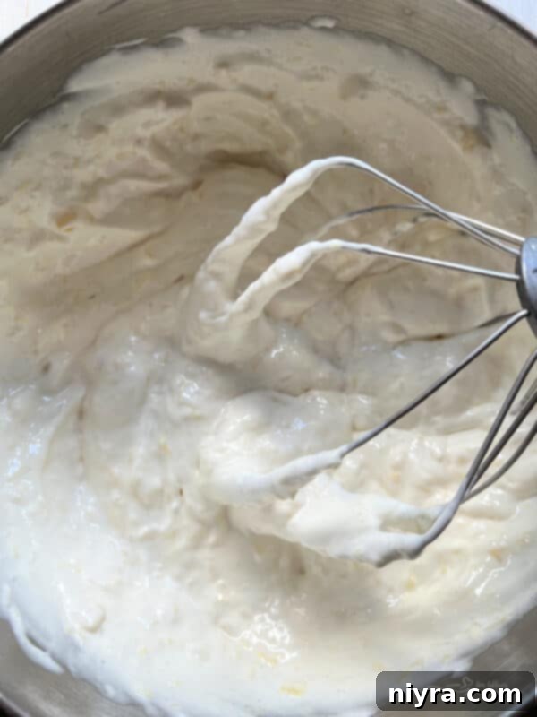 Cake mix and crushed pineapple being mixed in a large bowl