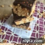 Chewy Chocolate Peanut Butter Bars stacked on a napkin, showcasing their layers