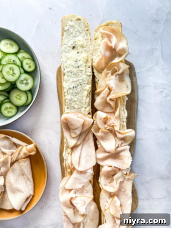 Step 6: Layering thinly sliced deli turkey over the ranch spread on the baguette.