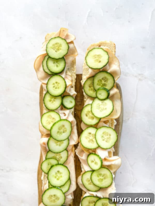 Step 7: Adding the final layer of fresh cucumber slices onto the turkey.