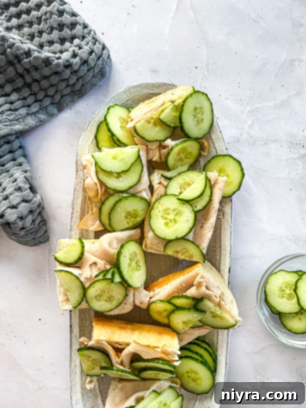 Ingredients for Turkey Ranch Baguettes laid out on a table: baguette, turkey, cucumbers, cream cheese, mayo, and ranch seasoning.