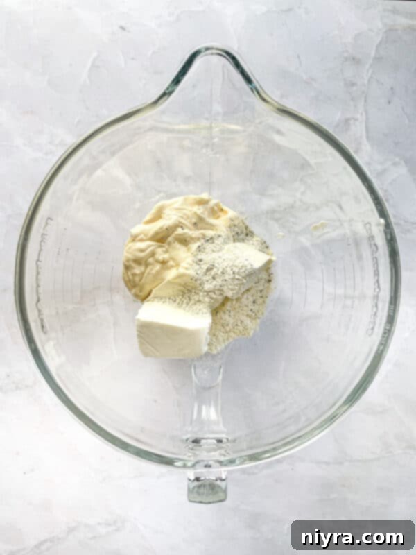 Step 1: Combining mayonnaise, cream cheese, and ranch seasoning in a mixer.
