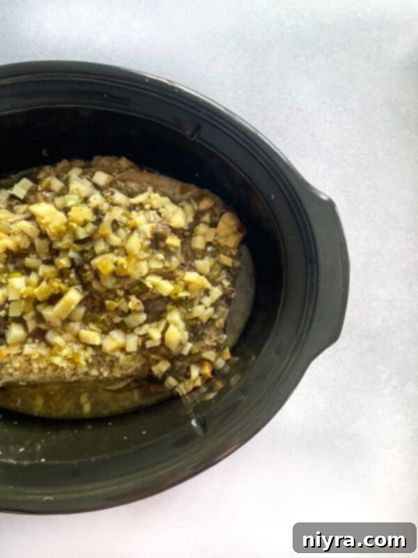 Squeezing orange juice over pork and aromatics in a slow cooker