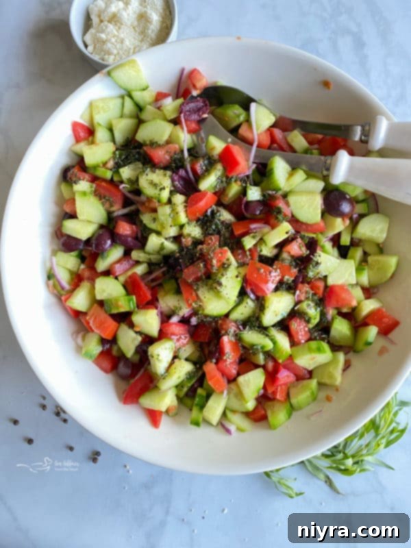 Refreshing Greek Cucumber Salad 7 Vinegar being poured over a bowl of cucumbers, tomatoes, and red onion