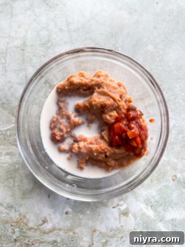 Mixing refried beans, milk, and salsa in a bowl