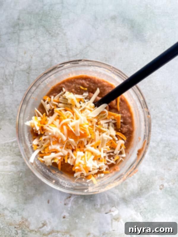 Cheese being folded into the refried bean mixture