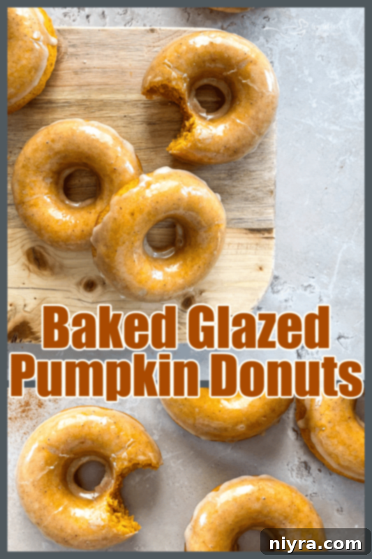 A stack of beautifully glazed baked pumpkin donuts on a white plate, ready to be served