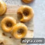 Glazed Baked Pumpkin Donuts with a bite taken out, showing the moist interior