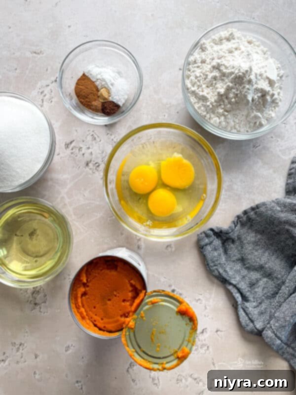 Assorted ingredients laid out for Glazed Baked Pumpkin Donuts, including pumpkin puree, spices, flour, and eggs