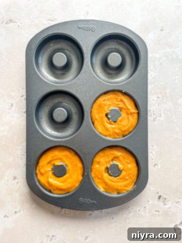 Spoon about 3-4 Tablespoons of donut batter into each donut section of a baking pan