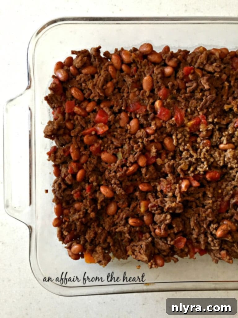 Loaded Tater Tot Taco Bake 7 Seasoned beef, RO*TEL, and pinto bean mixture spread evenly in the bottom of a 9x13 inch baking dish.