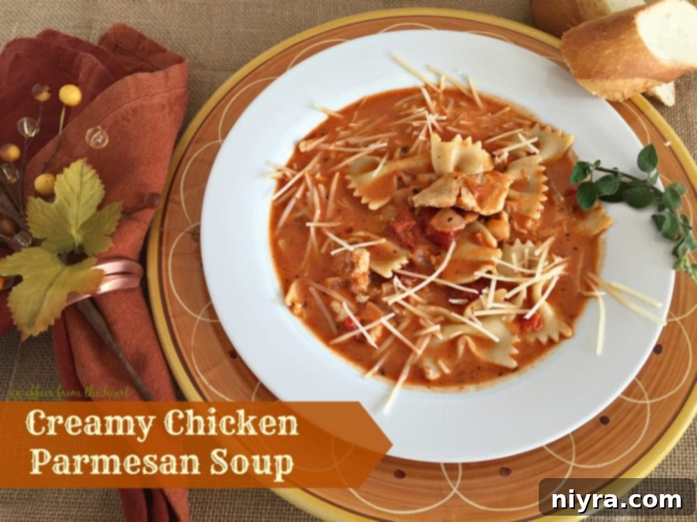 Creamy Chicken Parmesan Soup in a white bowl with a side of garlic bread