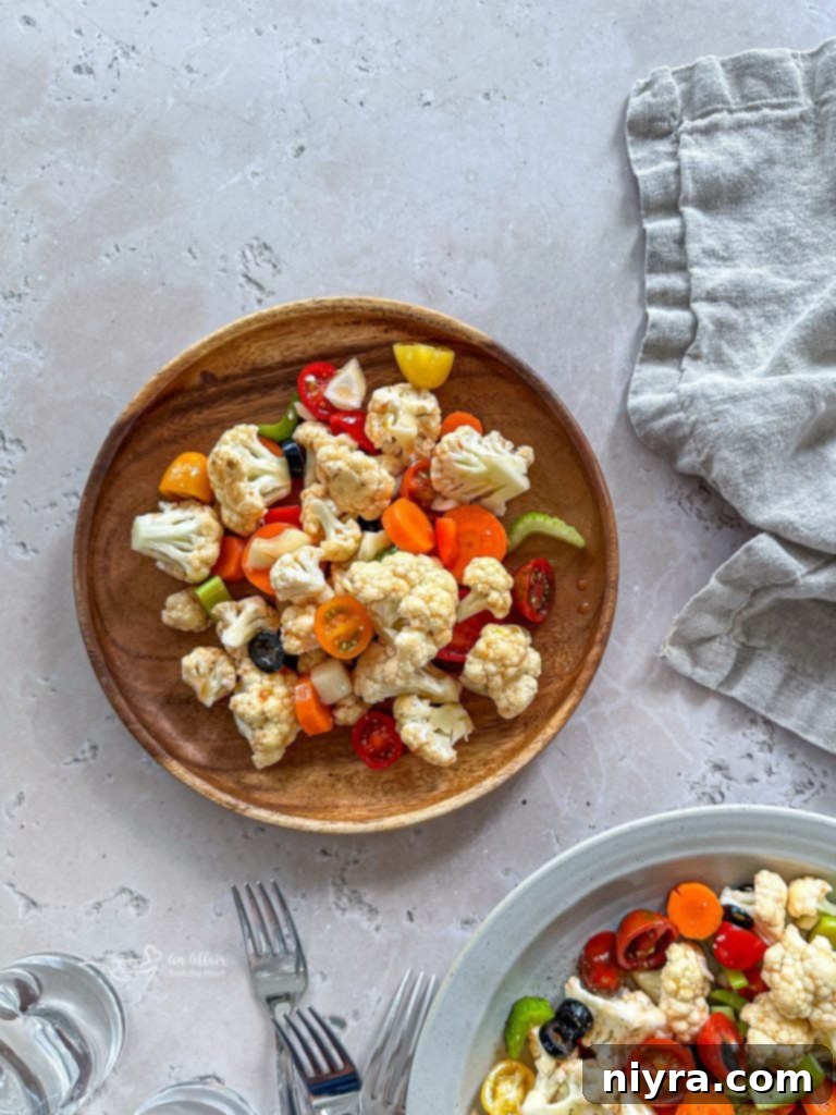 Colorful marinated vegetable salad in a clear bowl, with a serving spoon.