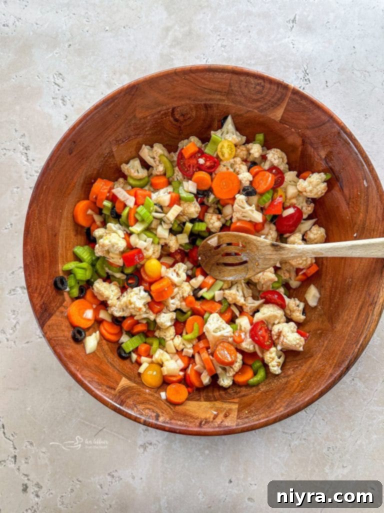 Pouring the dressing over chopped vegetables in a bowl.