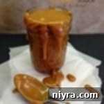 caramel sauce in a jar and dripping off the sides on to parchment paper with a spoon covered in the sauce. Text homemade salted caramel sauce