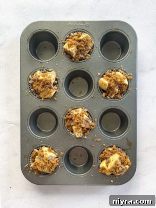 Cinnamon roll pieces in muffin cups, topped with toffee bits and brown sugar.