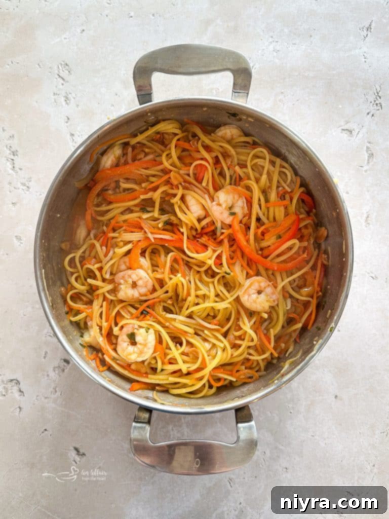 Close-up of a bowl of One-Pot Pad Thai garnished with peanuts, cilantro, and lime.