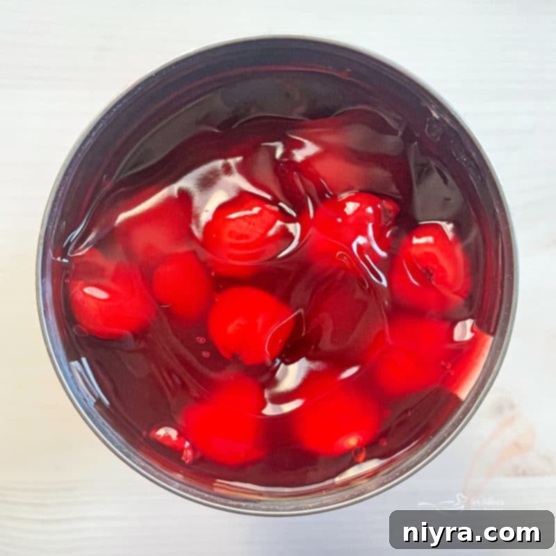 A bowl brimming with fresh, ripe cherries, showcasing their deep red color and readiness to be incorporated into a delicious dessert.