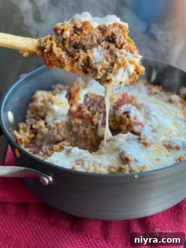 A close-up shot of a Stuffed Pepper Skillet dish, steaming hot and ready to serve, featuring ground beef, rice, bell peppers, and tomatoes.