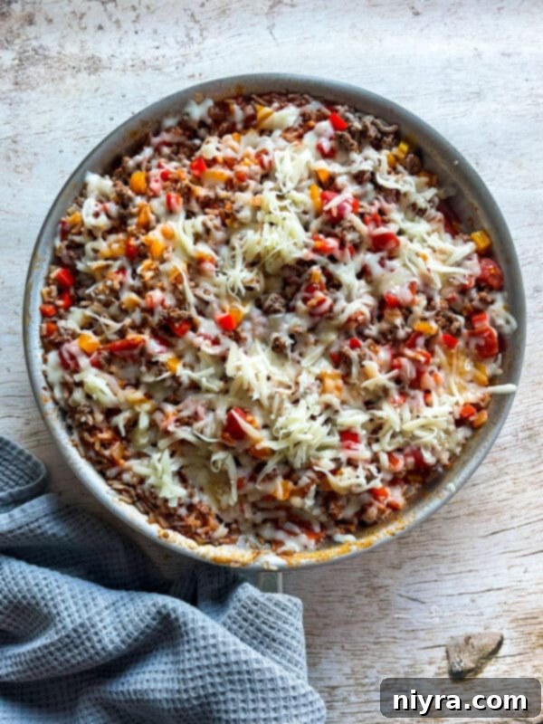 A close-up shot of the finished Stuffed Pepper Skillet, featuring melted mozzarella cheese over the top of the savory mixture of ground beef, rice, and peppers.