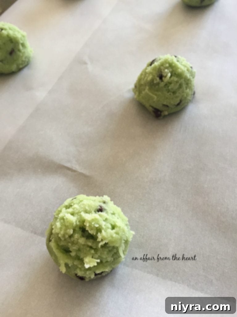 Refreshing Mint Chocolate Chip Cookies 5 Close-up of green cookie dough balls on a parchment-lined baking sheet