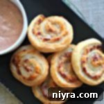 Savory Reuben Spirals 11 Reuben Pinwheels with thousand island dressing on a black serving plate