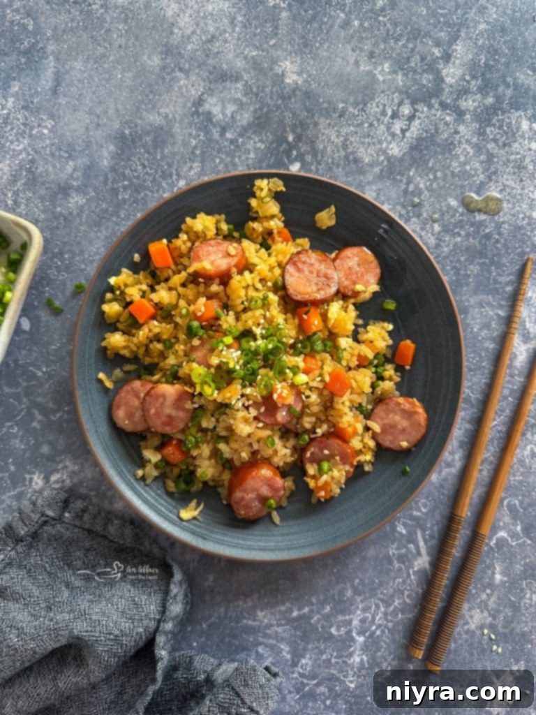 Overhead shot of Kielbasa Fried Rice in a pan, with a serving spoon.