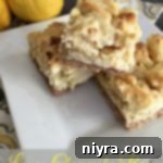 Zesty Lemon Cheesecake Bars 6 Bars stacked on a white plate with text "Lemon Cheesecake Bars"