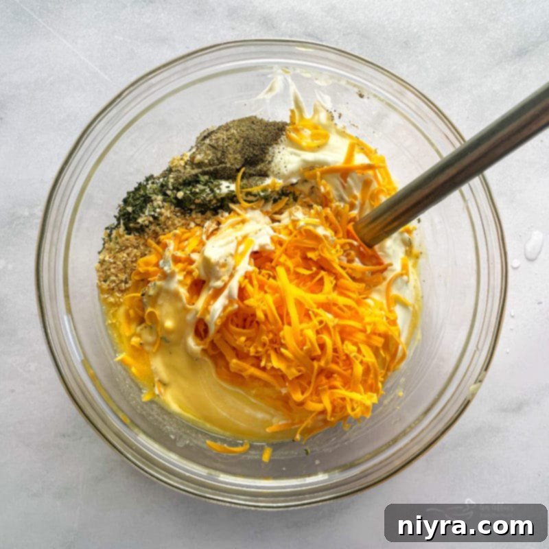 Combined soup, sour cream, 1/4 cup of melted butter, 1 1/2 cups cheese, onion pepper and parsley in a bowl.