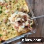 Scooping the Chicken Cordon Bleu Casserole with Rice out of a clear baking dish.