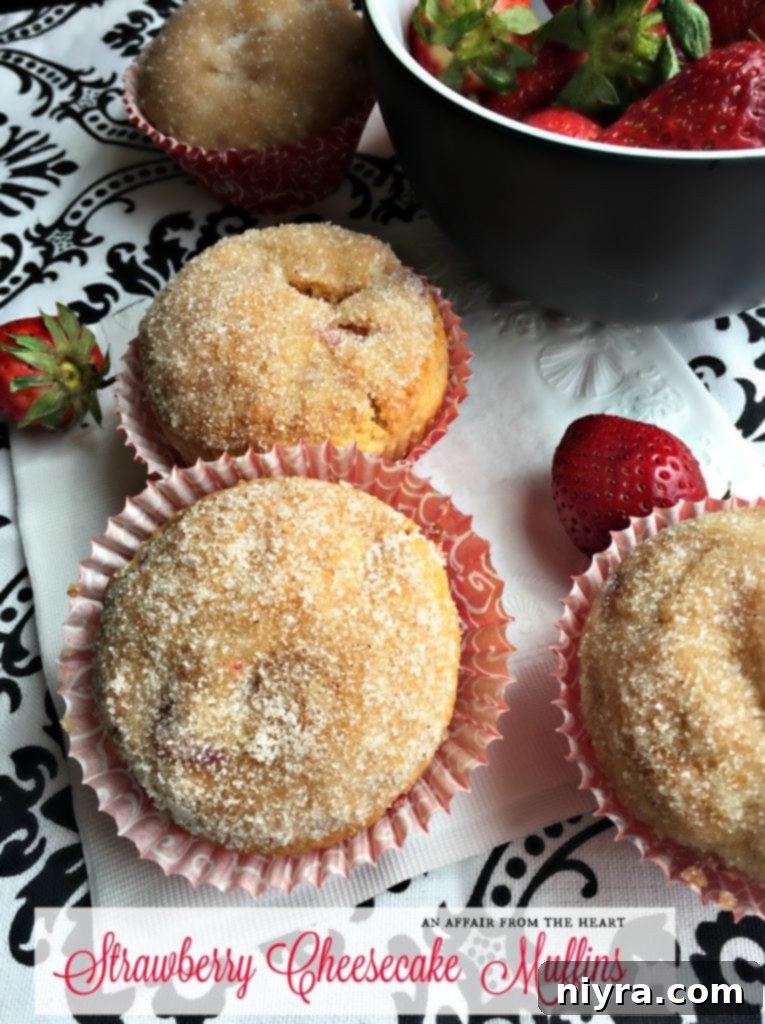 Close-up of a perfectly baked Strawberry Cheesecake Muffin with a visible cheesecake swirl and cinnamon sugar topping