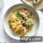 Close up of Chicken Mushroom Florentine pasta on a white plate.