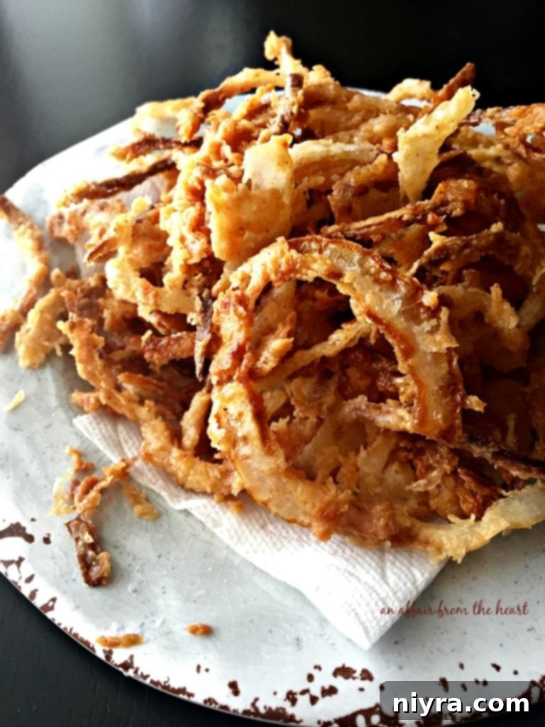 A close-up of delicious Homemade Onion Strings on a light blue plate, showcasing their golden crispness.