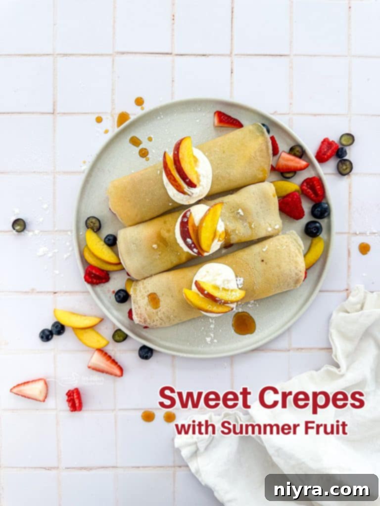 Hero shot of rolled sweet crepes topped with an abundance of fresh summer fruits and whipped cream on a marble platter.
