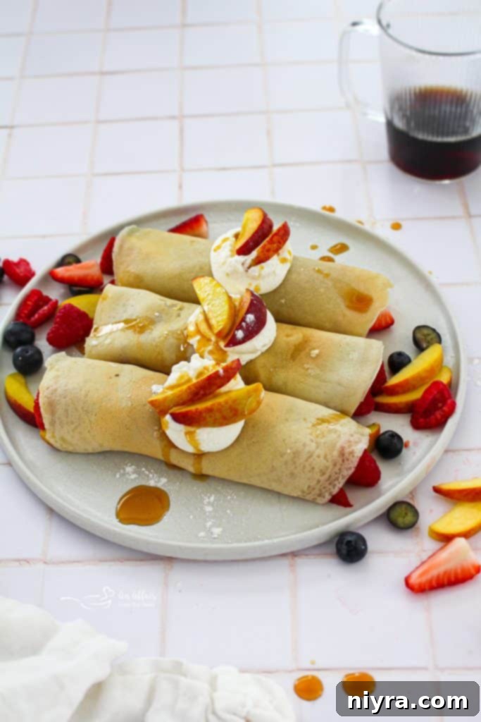 Close-up shot of a stack of golden-brown sweet crepes, ready to be filled, with fresh summer berries in the background.
