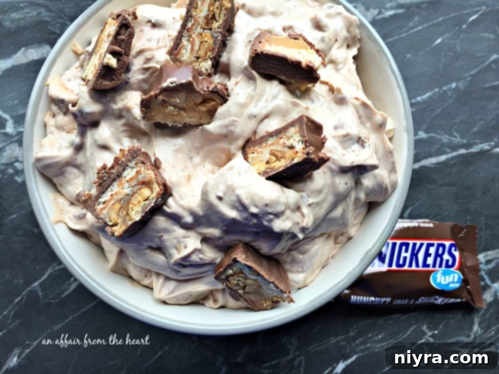 Snickers Dip, a fluffy dessert dip with candy bars and caramel drizzle